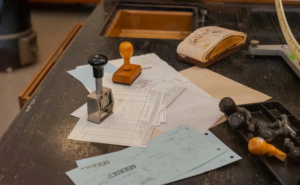 Cluttered desk with office stamps on top of various documents in an office setting.