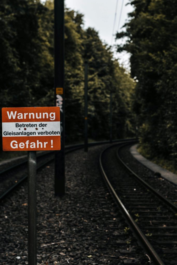 Railway tracks with a warning sign in a forested area of Bielefeld, Germany.